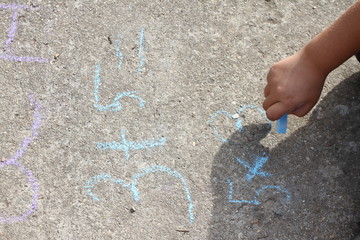 Kid hands writing and counting on mathematical equations with colored chalks on a pavement. School and vacation concept. Education concept. School and fun time. learning in nature.