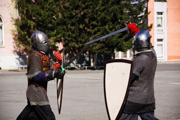 Two men in knightly armor are fighting with swords
