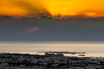 Aufnahme eines Sonnenuntergangs über der Küste von Dubai mit hochstehenden Wolken und strahlendem...