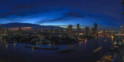 Fototapeta premium Panoramaaufnahme von Bangkok mit Chao Phraya Fluss aus Vogelperspektive fotografiert Abends zur blauen Stunde bei leichter Bewölkung im September 2016