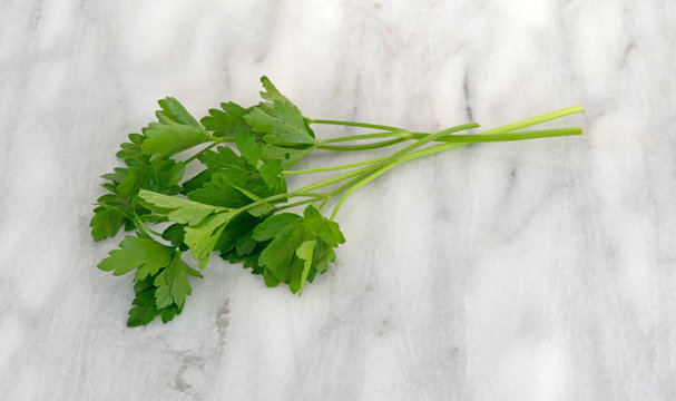 Parsley sprigs on a marble counter top.