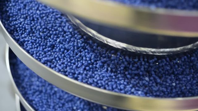 The blue round granules move up the vibrating screw conveyor.