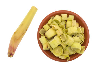 Lemon grass sections in a small bowl with a stalk to the side isolated on a white background.