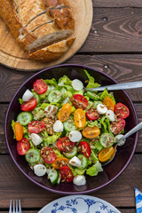 Lettuce and tomatoes salad on wooden table. In the garden. 
