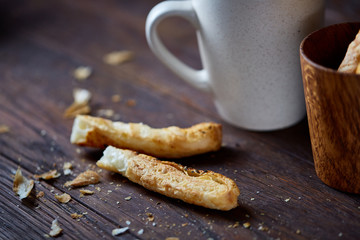 Coffee cup and breadsticks on an old wooden background, close-up, selective focus.