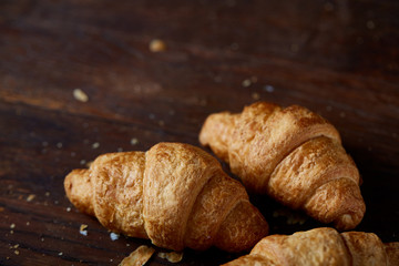 Tasty buttery croissants on an old wooden table, close-up, selective focus, shallow depth of field.