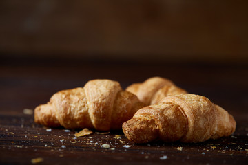 Tasty buttery croissants on an old wooden table, close-up, selective focus, shallow depth of field.