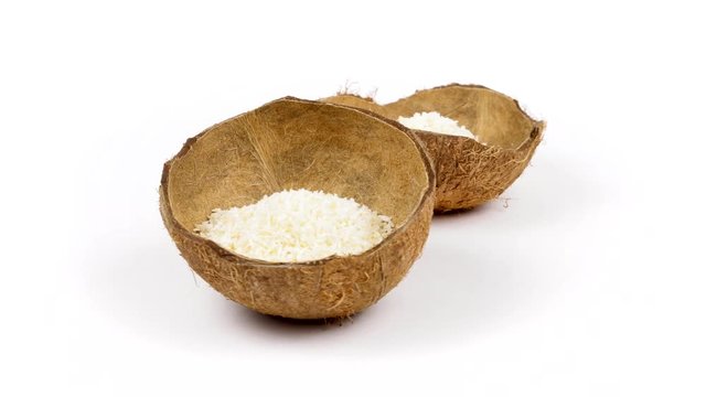 Two shells halves of tropical coconut with dried white coconut flakes rotating on white isolated background. Healthy tropical fruits. Loopable seamless cocos rotating