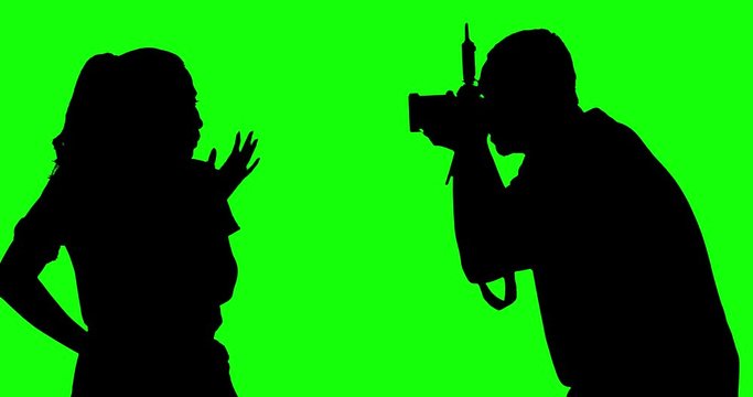 Silhouette of unknown photographer taking picture of model in the studio, shot in 4k resolution with green screen background