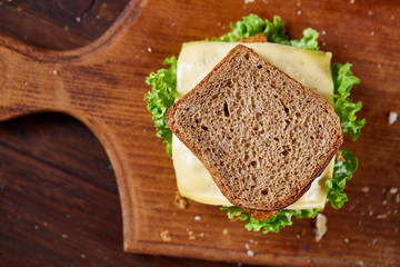 Tasty and fresh sandwiches on cutting board over a dark wooden background, close-up