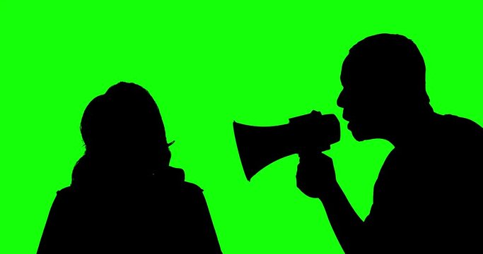 Silhouette of man scolding a woman while shouting with a megaphone in the studio, shot in 4k resolution with green screen background