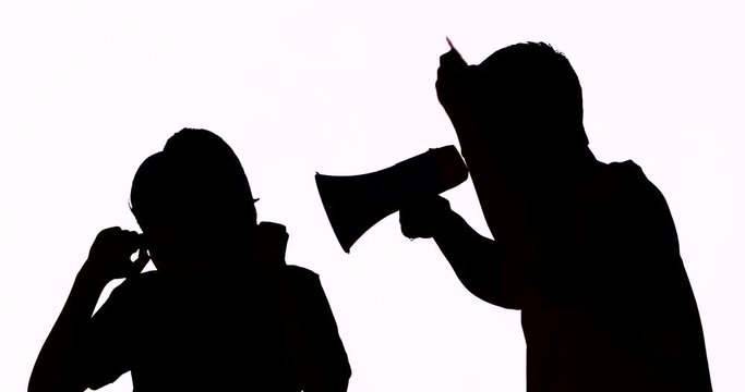 Silhouette of unknown man scolding a woman while pointing and shouting with a megaphone in the studio, isolated on white background. Shot in 4k resolution