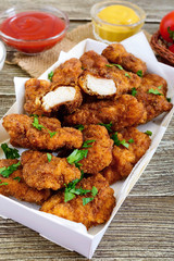 Chicken nuggets. Pieces of deep-fried crispy meat,  with different sauces on a wooden table. Traditional snack.