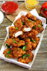 Chicken nuggets. Pieces of deep-fried crispy meat,  with different sauces on a wooden table. Traditional snack.