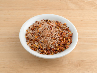 Greek spice rub in a white bowl on a wood table illuminated with natural light.