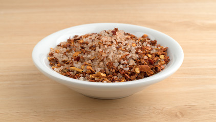 Greek spice rub in a white bowl atop a wood table.
