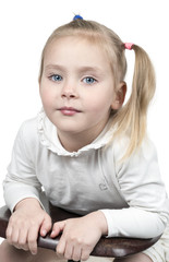 Portrait of a pretty little girl with a ponytail sideways leaning on a chair isolated on white background