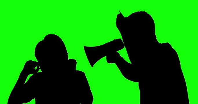 Silhouette of unidentified man scolding a woman with a megaphone while pointing and shouting at her in the studio. Shot in 4k resolution with green screen background