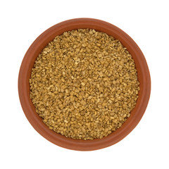 Top view of a bowl of gold sugar on a white background.