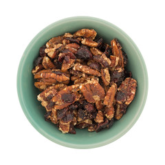 Top view of sugar glazed pecans with dried cranberries in a green bowl isolated on a white background.