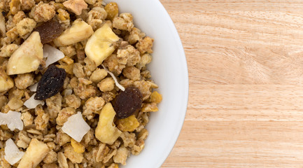 Top close view of fruit mix granola in a bowl atop a wood table.