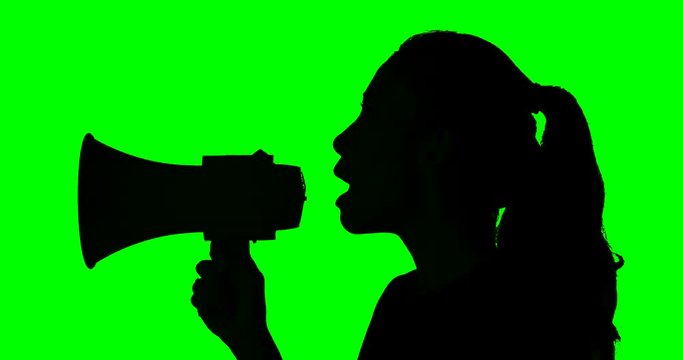 Silhouette of a woman yelling with a megaphone in the studio, shot in 4k resolution with green screen background