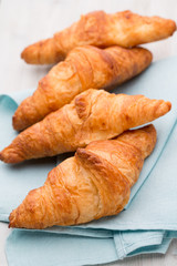Tasty buttery croissants on old wooden table.