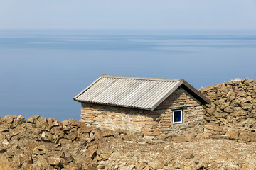 Traditional cottage made of lime stone at the blue calm sea. At Aleklinta on the island Oland, Sweden