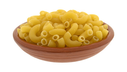 Side view of elbow macaroni in a small red clay bowl isolated on a white background.