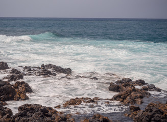 Fototapeta na wymiar Blue sea waves crashing on the shore at Playa de la Enramada in Teneriffe, Spain EU