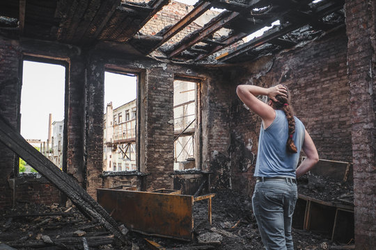 Sad Man Holds His Head By Hand And Cry In Burnt Out House After Disaster, Consequences Of Fire