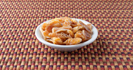 Dried mandarin orange slices in a small bowl atop a colorful place mat.