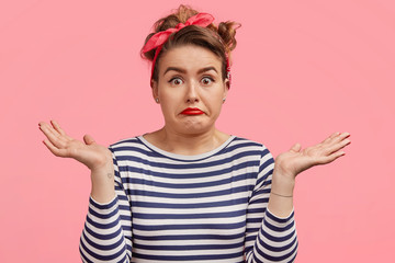 Portrait of clueless pinup girl looks hesitant and puzzled, shrugs shoulders, can`t make decision...