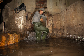 Sewer worker in underground flooded sewage collector - obrazy, fototapety, plakaty