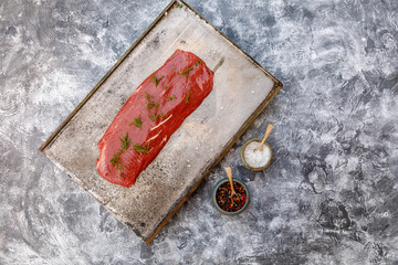Beef Flat Iron steak on old metallic smoke tray on gray concrete background, top view, copy space