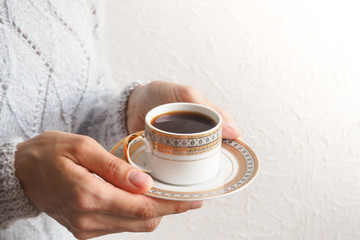 A Cup of black coffee in the hands of the white wall.