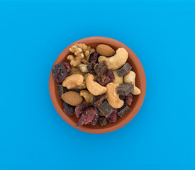 Top view of a chocolate and nut mixture in a bowl on a blue plastic cutting board.