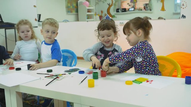 Children's developing a game room. Emotions of young children during entertaining classes. children paint with finger paints on white sheets of paper. children stretch their hands in the paint smeared