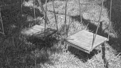 empty, abandoned children's horror swings, black and white