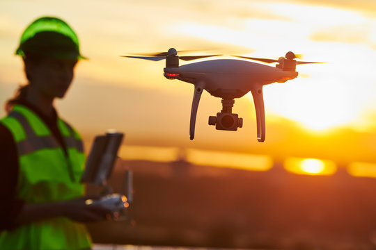 Drone inspection. Operator inspecting construction building site flying with drone. sunset