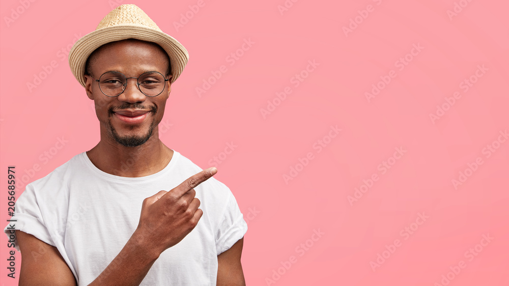 Wall mural check this out. horizontal shot of positive funny african american male in straw hat points with for