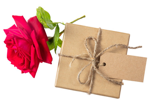 Rose red flower and a gift box with a blank tag on a white background, top view, space for text