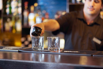 Bartender man pours whiskey to the client of the hotel bar. The concept of service. Toning