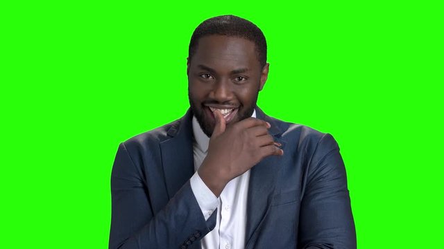Sexy afro american man on green screen. Portrait of a flirting african american man winking with eye on chroma key background. Young flirtatious businessman.