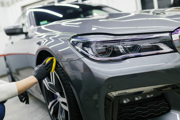 A man cleaning car with cloth, car detailing (or valeting) concept. Selective focus.