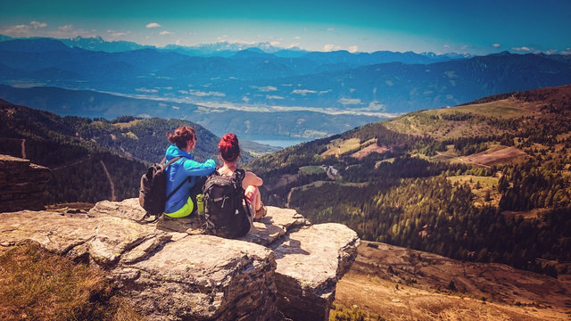 two women sitting on the top of a mountain with wonderful view