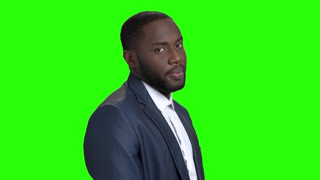 Flirtatious afro-american businessman on green screen. Portrait of dark-skinned flirting man on chroma key background. Self-assertive macho-man.