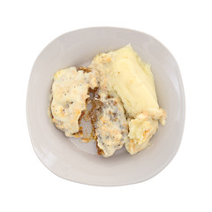 Top view of a fried beef steak with gravy and mashed potatoes on a plate isolated on a white background.