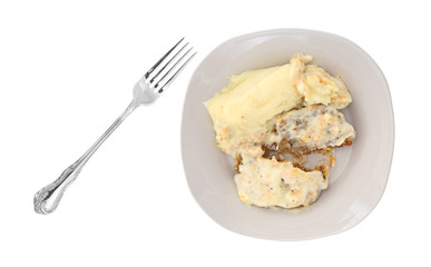 Fried beef steak with gravy and mashed potatoes with a fork to the side isolated on a white background.
