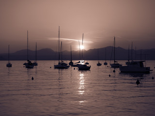 Sailboats moored in Lake Garda, Italy, at sunset.